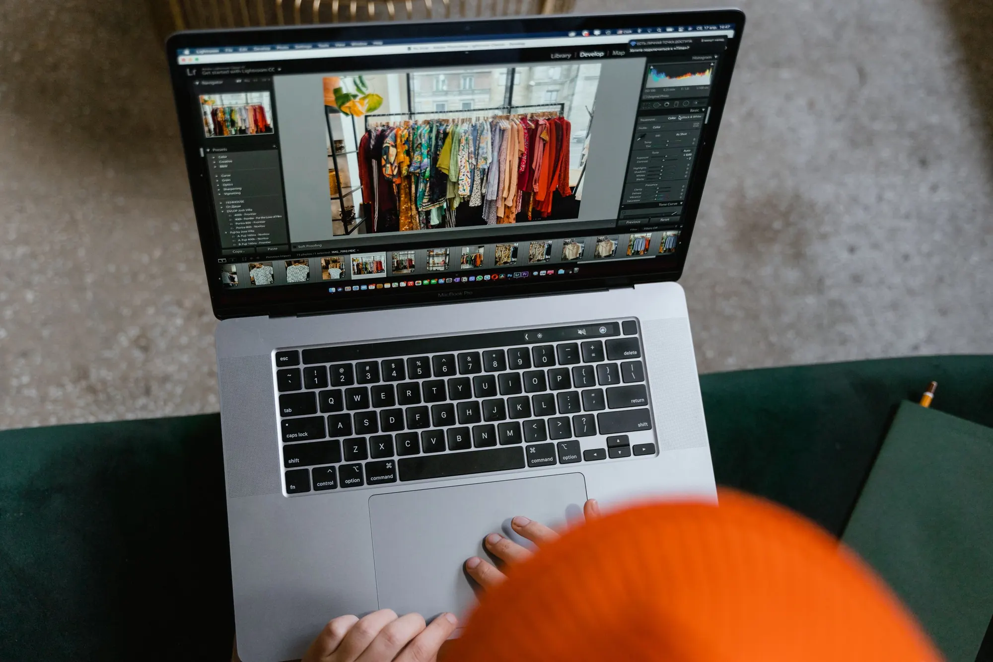 Overhead view of hands on a laptop, editing a shop's product photo of a clothing rack in a photo catalog app